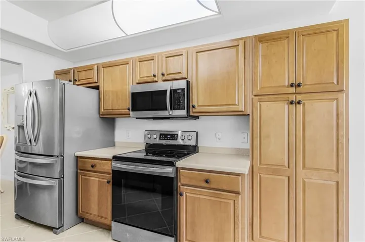 Kitchen featuring wood-finish cabinetry, stainless steel appliances, and light-toned countertops