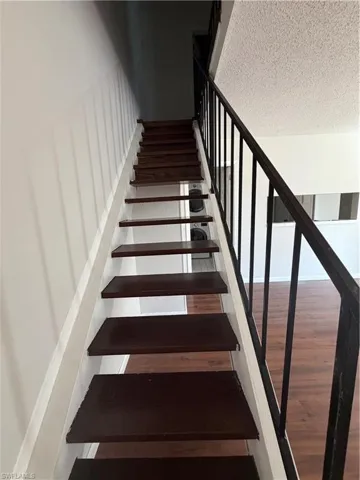 Stairway featuring a textured ceiling