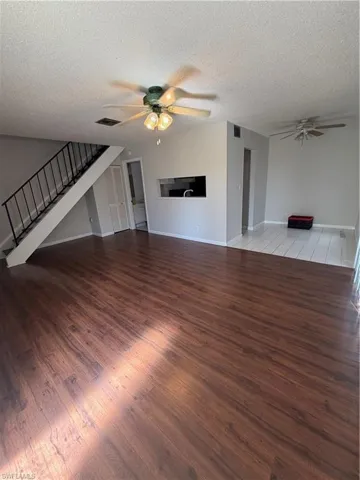 Unfurnished living room with a ceiling fan, light wood-type flooring, and a textured ceiling