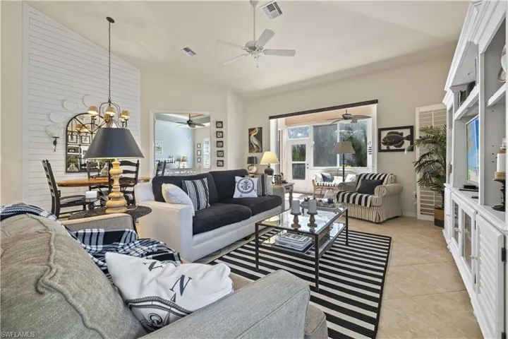 Living room with light tile patterned flooring, high vaulted ceiling, and a notable chandelier