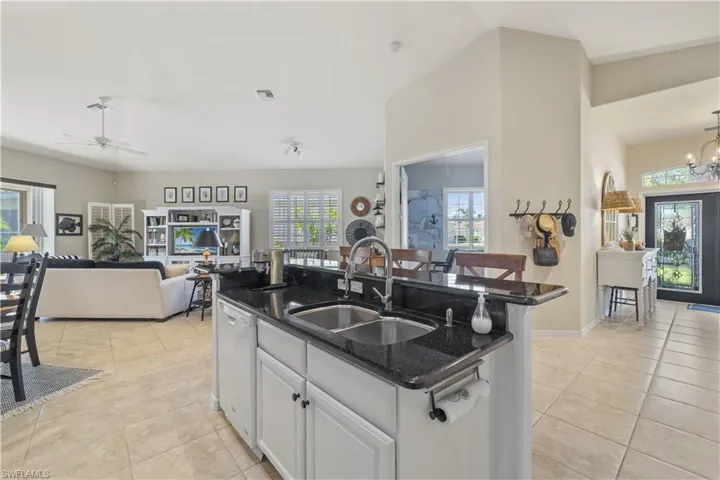 Kitchen featuring dishwasher, sink, a kitchen island with sink, white cabinets, and ceiling fan with notable chandelier