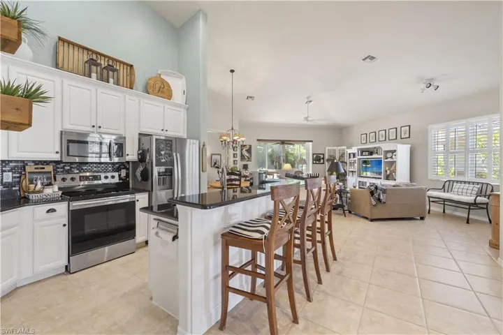 Kitchen featuring a wealth of natural light, stainless steel appliances, a kitchen island, a breakfast bar, and white cabinets