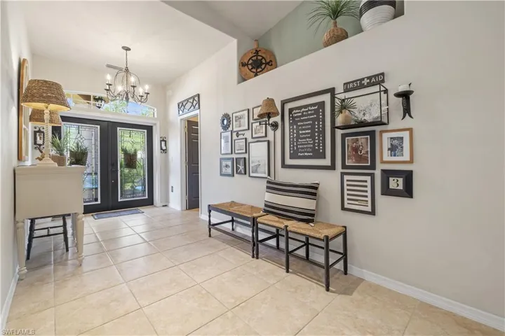 Tiled entrance foyer with french doors and a chandelier