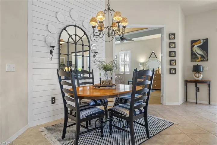 Tiled dining space with ceiling fan with notable chandelier