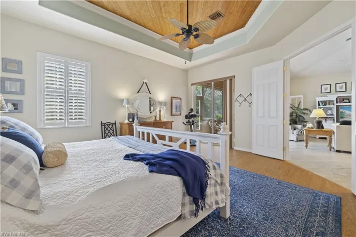 Bedroom featuring ceiling fan, wooden ceiling, crown molding, hardwood / wood-style floors, and a tray ceiling