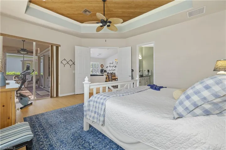 Bedroom with access to exterior, a raised ceiling, ceiling fan, hardwood / wood-style flooring, and wooden ceiling