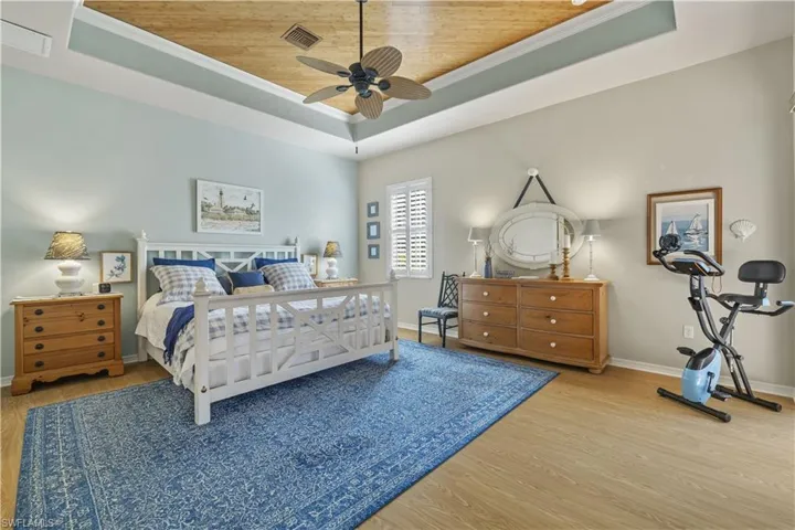 Bedroom featuring wood ceiling, a raised ceiling, ceiling fan, crown molding, and hardwood / wood-style flooring