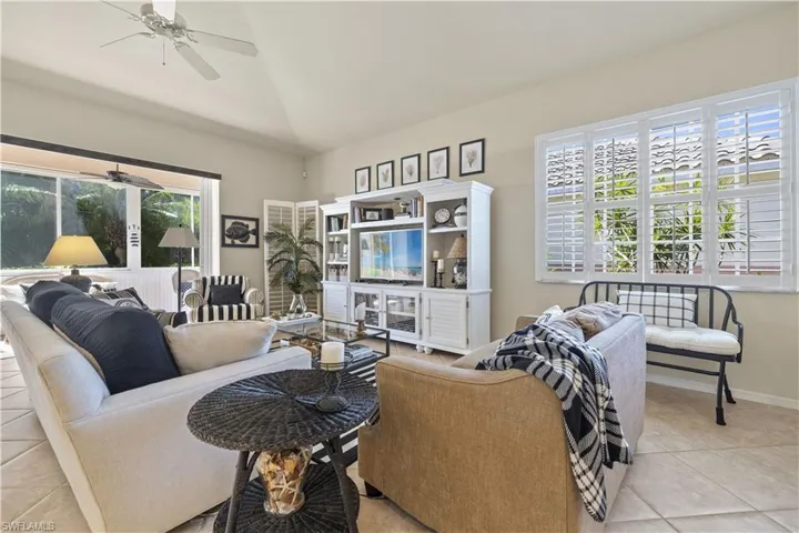 Living room featuring ceiling fan, light tile patterned floors, and vaulted ceiling