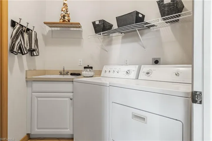 Clothes washing area with washer and clothes dryer, cabinets, and sink