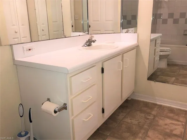 Full bathroom with baseboards, toilet, tile patterned floors, vanity, and  shower combination