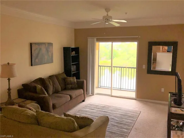 Carpeted living area featuring a ceiling fan, ornamental molding, and baseboards