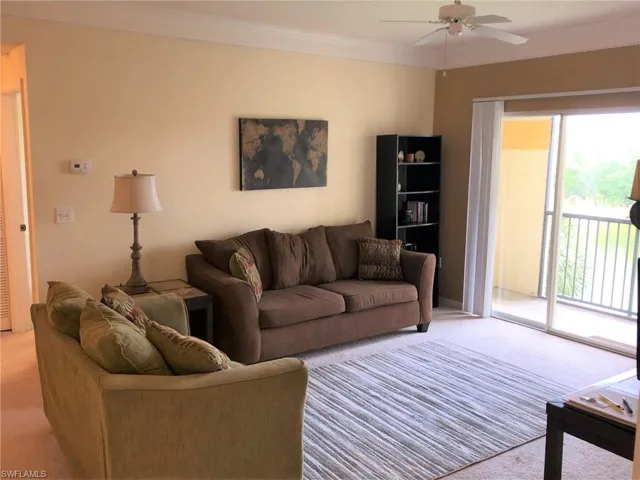 Living area featuring light carpet, ornamental molding, and a ceiling fan