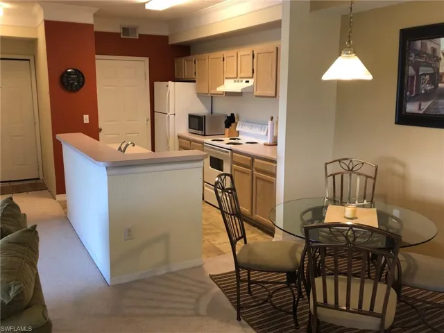 Kitchen featuring light countertops, visible vents, crown molding, white appliances, and under cabinet range hood