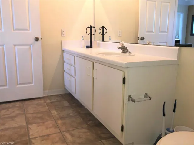 Bathroom featuring toilet, vanity, baseboards, and tile patterned flooring