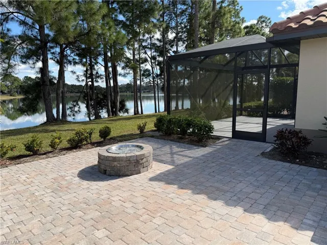 View of patio / terrace featuring an outdoor fire pit, glass enclosure, a sunroom, and a water view