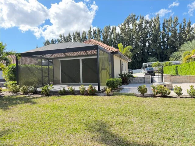 Back of property featuring a lanai, a patio area, a tile roof, a gate, and a sunroom