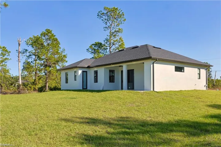 Back of property with a yard, stucco siding, and a patio