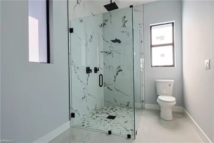 Full bath with a marble finish shower and marble finish floors