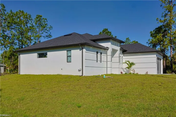 View of side of home with a yard, a shingled roof, and stucco siding