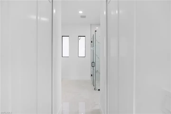 Hallway with recessed lighting, two narrow windows with dark frames, and light-toned flooring