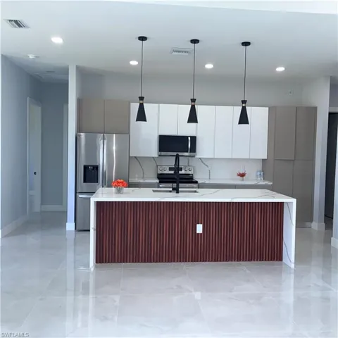 Kitchen featuring an expansive island with a wood-finish slatted facade and waterfall countertop