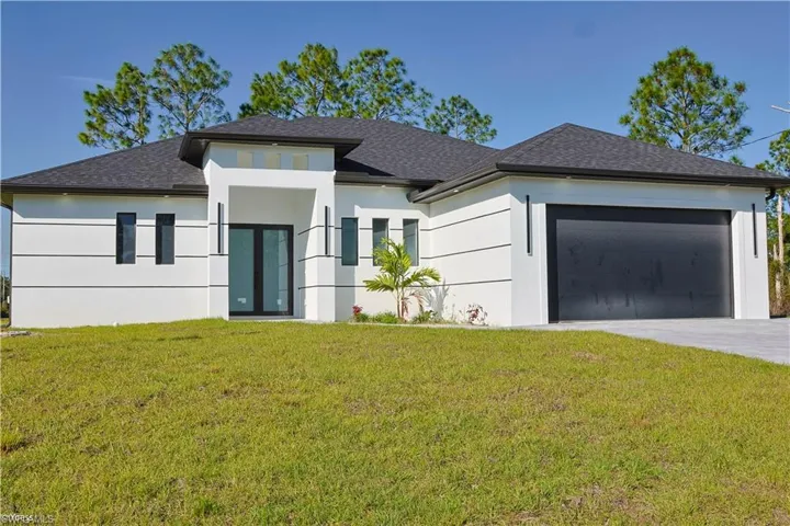 Prairie-style home with an attached garage, a front yard, roof with shingles, driveway, and stucco siding