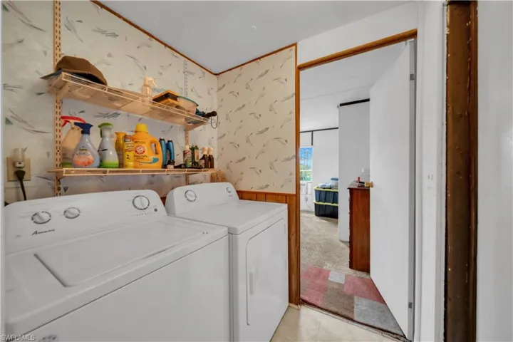 Laundry area featuring wallpapered walls, separate washer and dryer, light carpet, and wainscoting