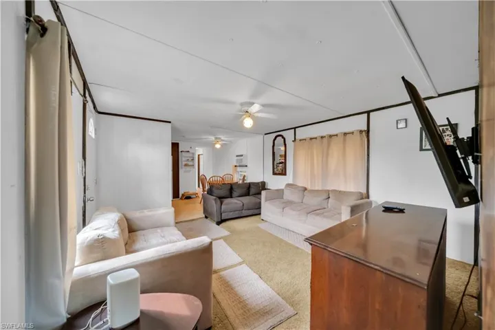 Carpeted living room featuring ceiling fan