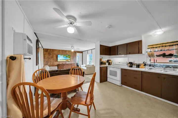 Kitchen with white electric range, a ceiling fan, a sink, light countertops, and dark brown cabinets