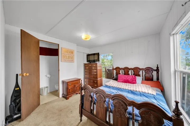Bedroom featuring light colored carpet and connected bathroom
