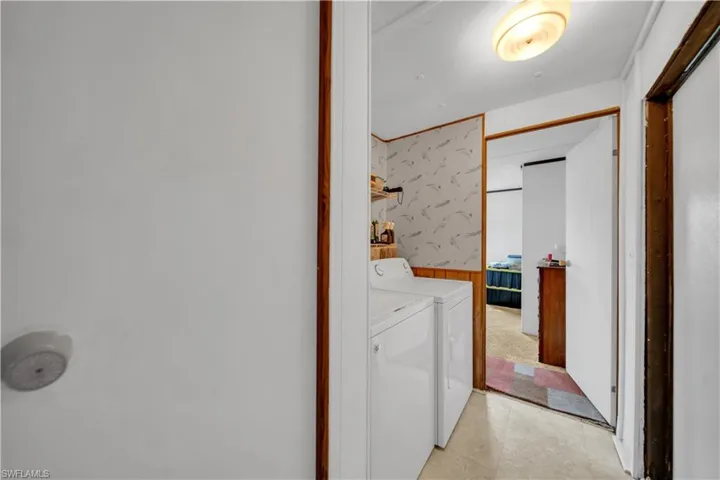 Washroom with washing machine and clothes dryer, wallpapered walls, and a wainscoted wall