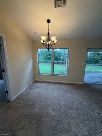 Neutral-toned carpeting, transom window, and a five-light chandelier