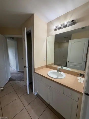 Bathroom vanity with a single basin sink, laminate countertop, and white cabinetry