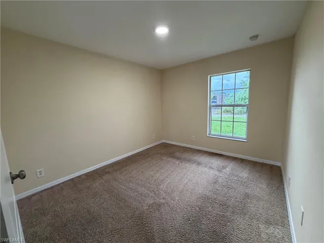 Recessed lighting, neutral wall paint, window with grid panes, wall-to-wall carpeting, and white trim