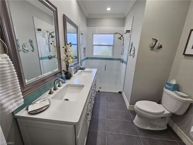 Bathroom featuring crown molding, a stall shower, double vanity, dark tile patterned flooring, and recessed lighting