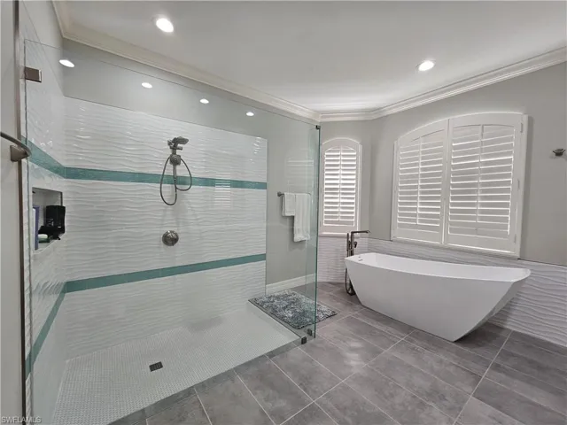 Bathroom featuring a shower stall, crown molding, a soaking tub, recessed lighting, and tile walls