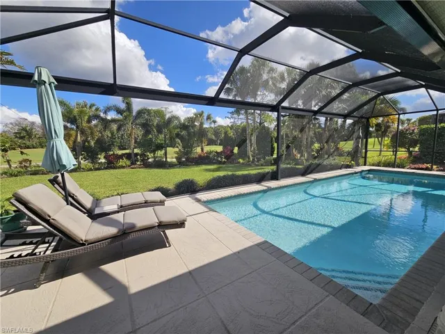 Outdoor pool with glass enclosure, a lawn, a sunroom, and a patio area