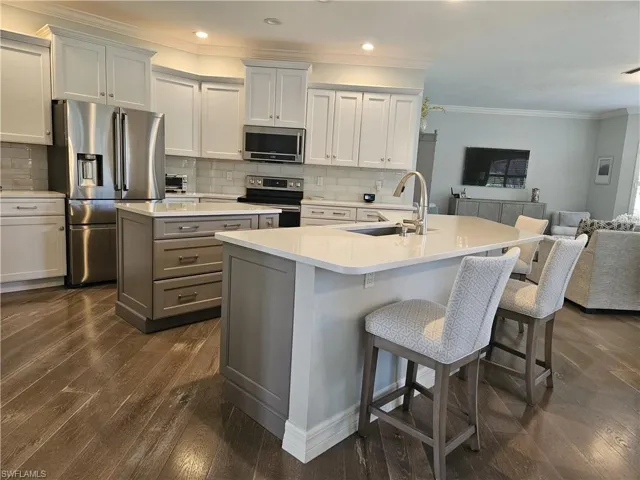Kitchen with crown molding, appliances with stainless steel finishes, dark wood-type flooring, decorative backsplash, and gray cabinets