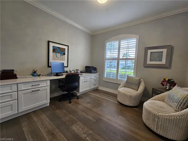 Office area featuring dark wood-style flooring, crown molding, and built in study area