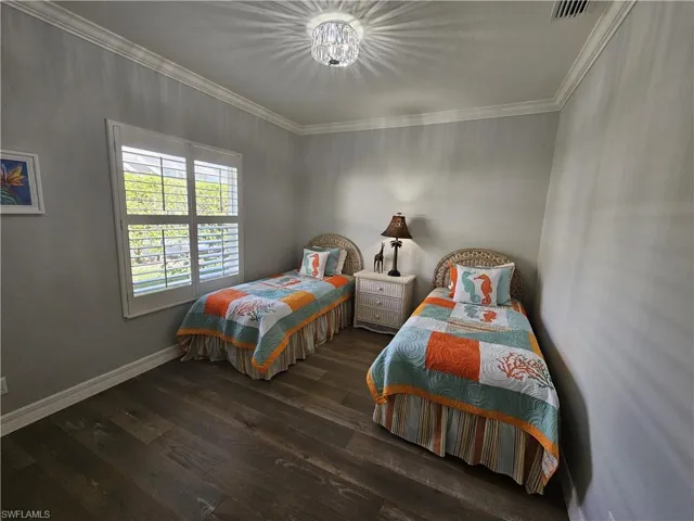 Bedroom with dark wood-style floors and ornamental molding