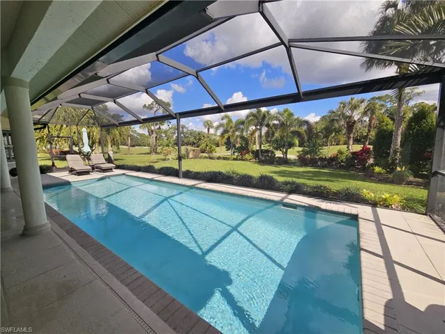 Swimming pool with a sunroom, glass enclosure, a lawn, and a patio area