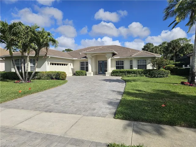 View of front of property with a front yard, stucco siding, a garage, and french doors