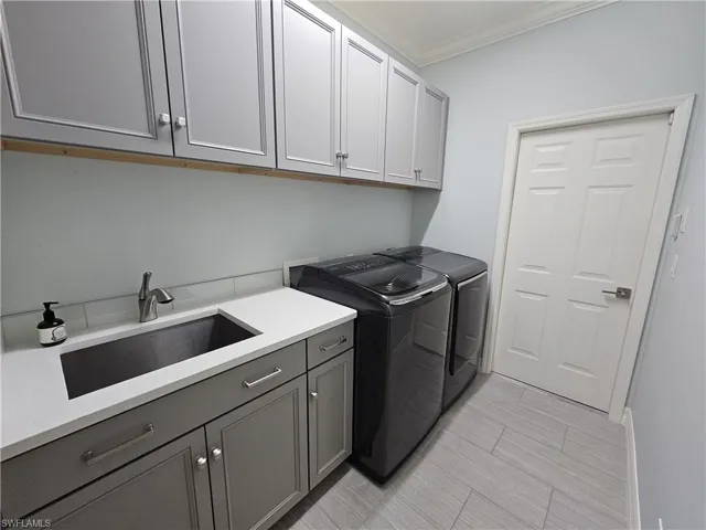 Washroom with cabinet space, ornamental molding, and separate washer and dryer