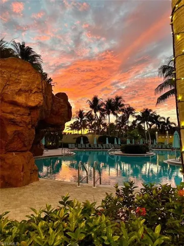 Pool at dusk featuring a patio area and a community pool