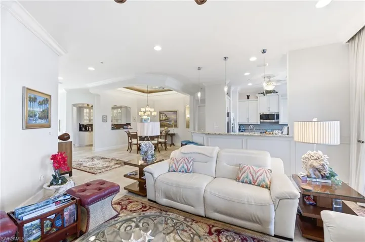 Living area featuring crown molding, arched walkways, and a chandelier