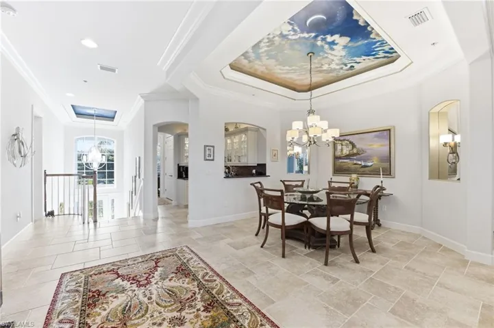 Dining room featuring a chandelier, a tray ceiling, crown molding, and arched walkways