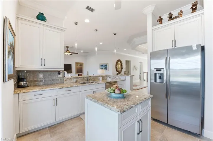 Kitchen with ornamental molding, stainless steel appliances, white cabinetry, a peninsula, and pendant lighting