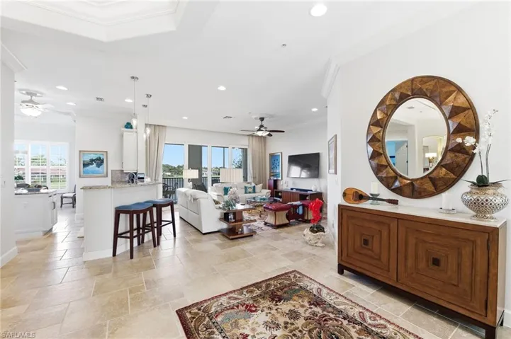 Living area featuring a ceiling fan, ornamental molding, stone tile floors, and recessed lighting