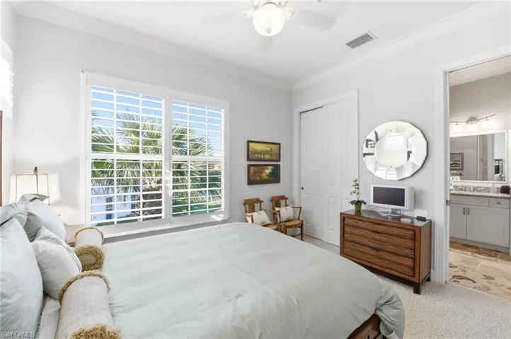 Carpeted bedroom with crown molding, a closet, ceiling fan, and ensuite bathroom