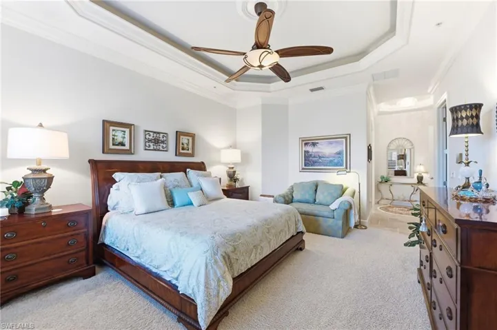 Bedroom featuring light carpet, crown molding, a ceiling fan, and a raised ceiling